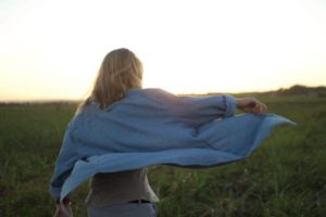 woman with shirt flying in wind in field