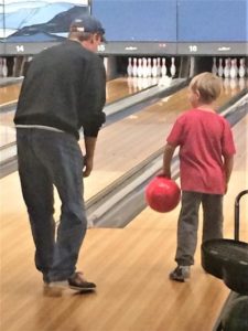 parent bowling with child happy